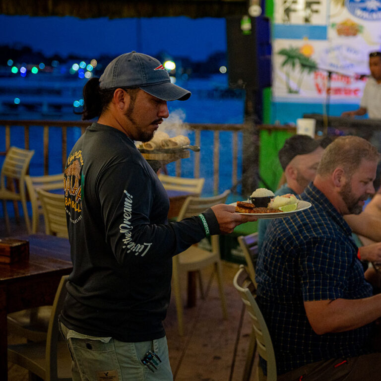 Server delivers fajitas and fresh fish fillet to guests at Palapa Bar and Grill in San Pedro, Belize